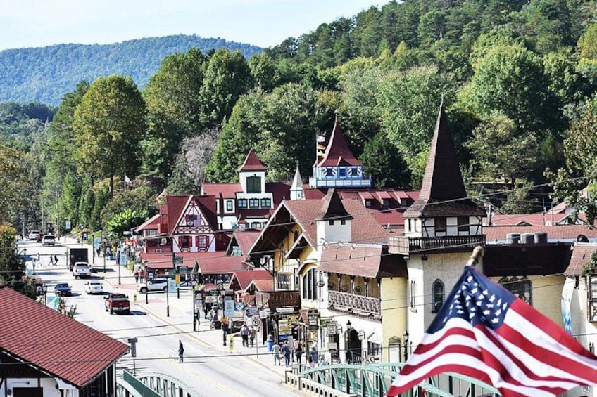 A town with traditional buildings, a prominent church steeple, and a mountain backdrop. 2