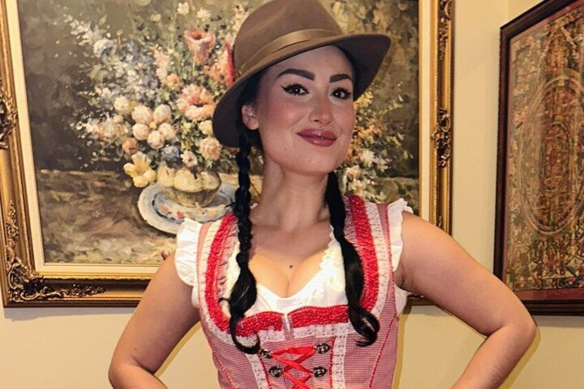 A person in traditional attire with braided hair, standing in front of a painting. 2
