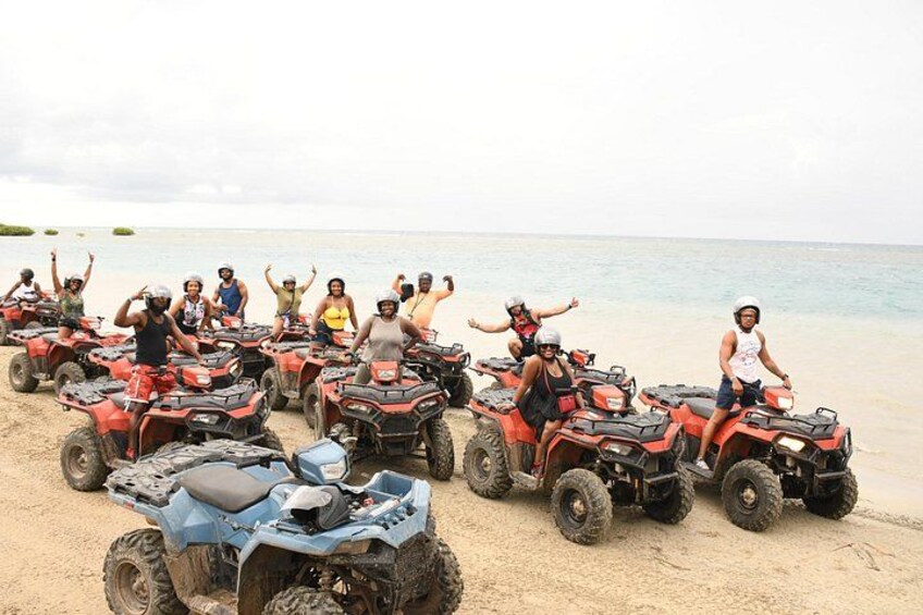 A group of people on ATVs on a sandy beach with the ocean in the background. 5