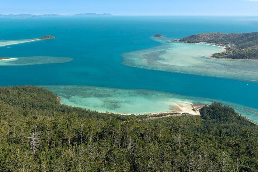 Un paisaje costero con aguas turquesas cristalinas, playas arenosas y colinas cubiertas de bosque denso. 3