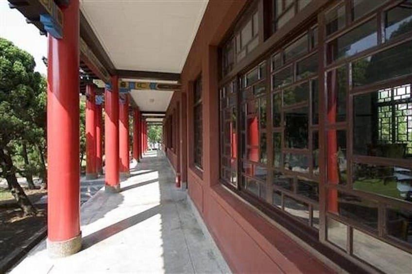 A covered walkway with red pillars and large windows. 2