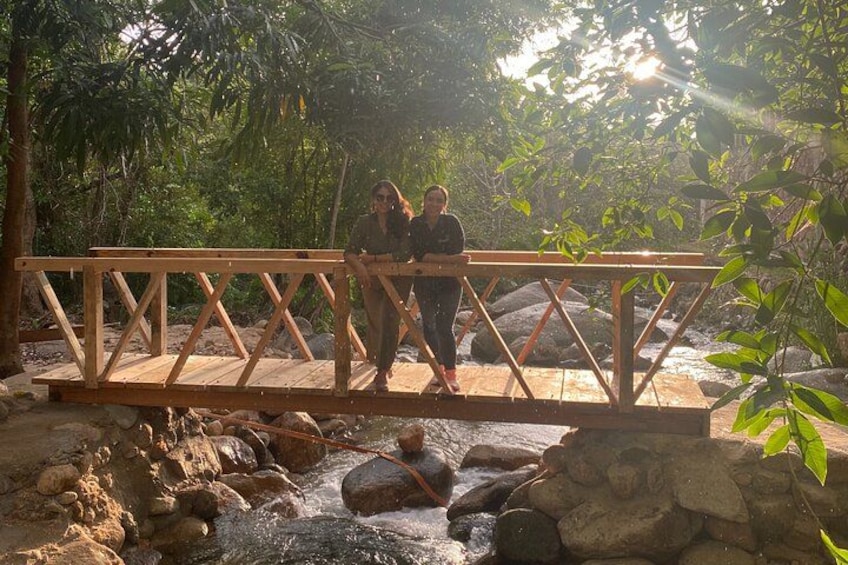 A wooden bridge over a stream with rocks and greenery around. 3