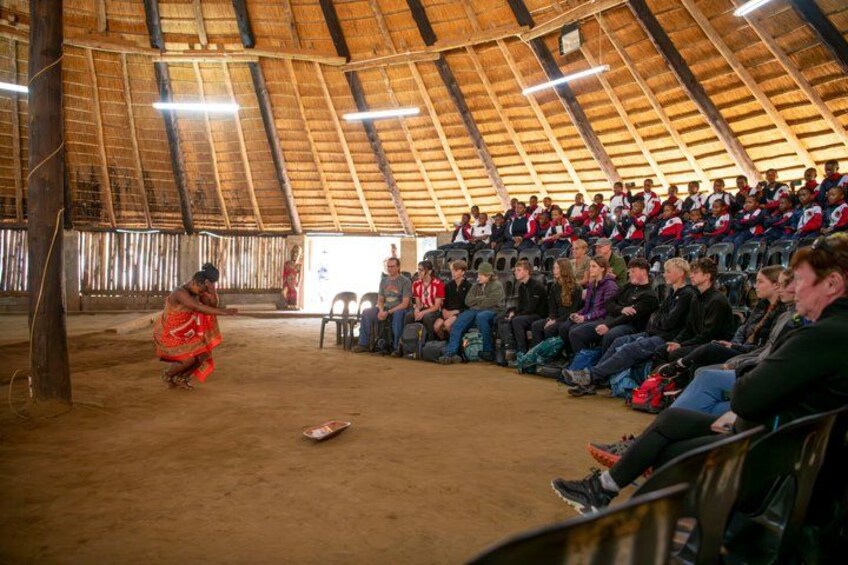 A large indoor gathering with a high wooden ceiling and a dirt floor. 5