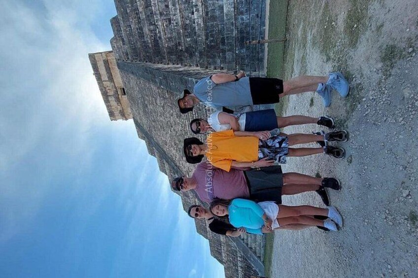 A group of people standing on a rocky surface with a historical building in the background. 3