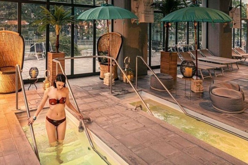 Een wellnessruimte met een zwembad, ligbedden en rieten meubilair. 2