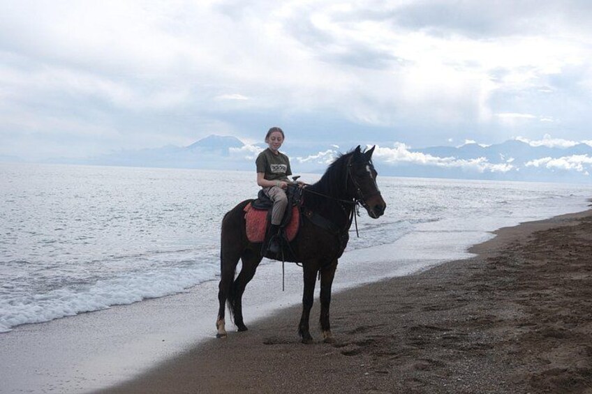 Une personne à cheval, chevauchant le long d’une plage, avec une montagne en arrière-plan. 3
