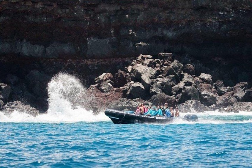 Un bateau avec des personnes à bord, au large d’une côte rocheuse. 3