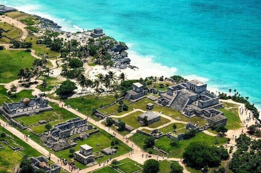 An aerial view of a coastal archaeological site with ancient structures and a beach. 1