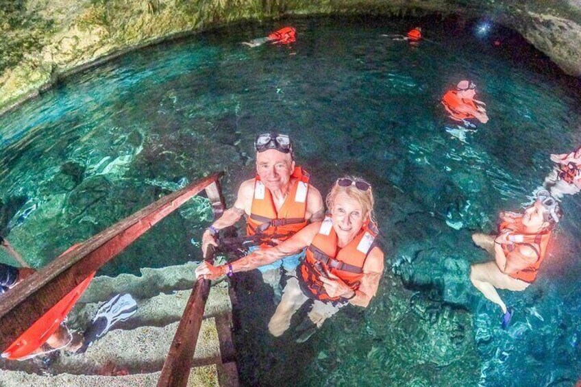 A group of people in a clear pool with wooden structures. 2