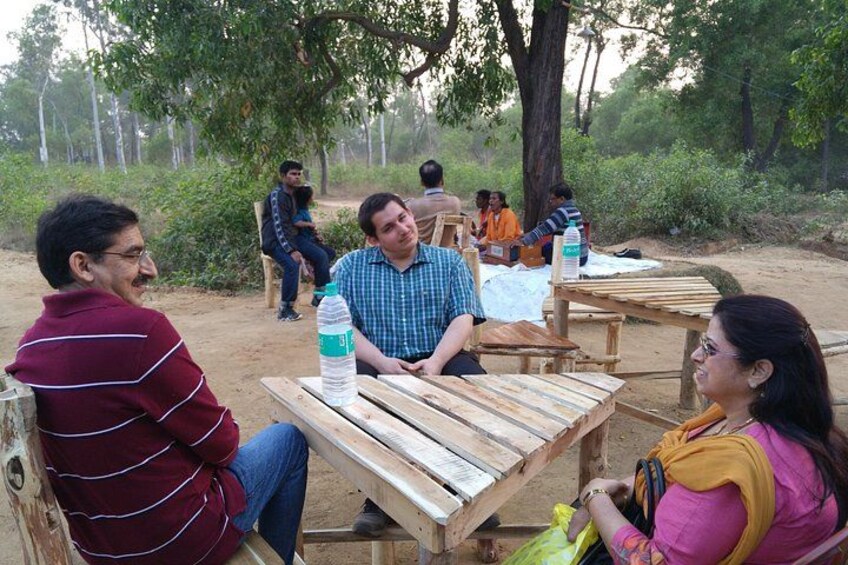 People sitting at wooden tables outdoors, engaged in conversation. 5