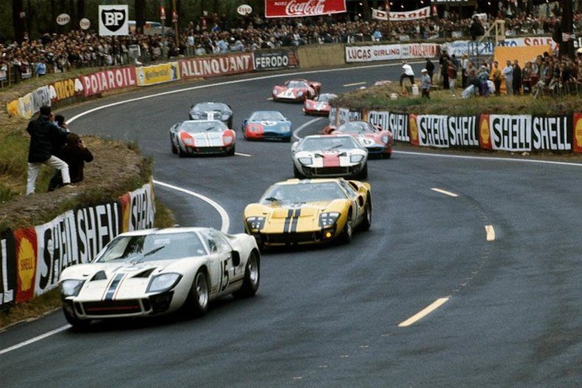 Ett motorsportevenemang där flera bilar tävlar på en bana, omgivna av åskådare och reklambanners. 2