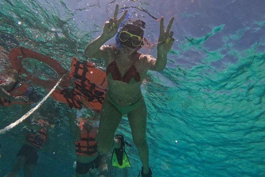 Una persona bajo el agua con un snorkel y aletas, haciendo un gesto de la paz. 4