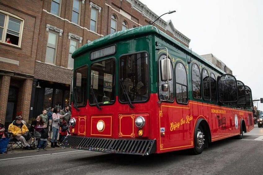 A vintage red and green bus with 'Enjoy the Ride' text, driving on a city street. 2