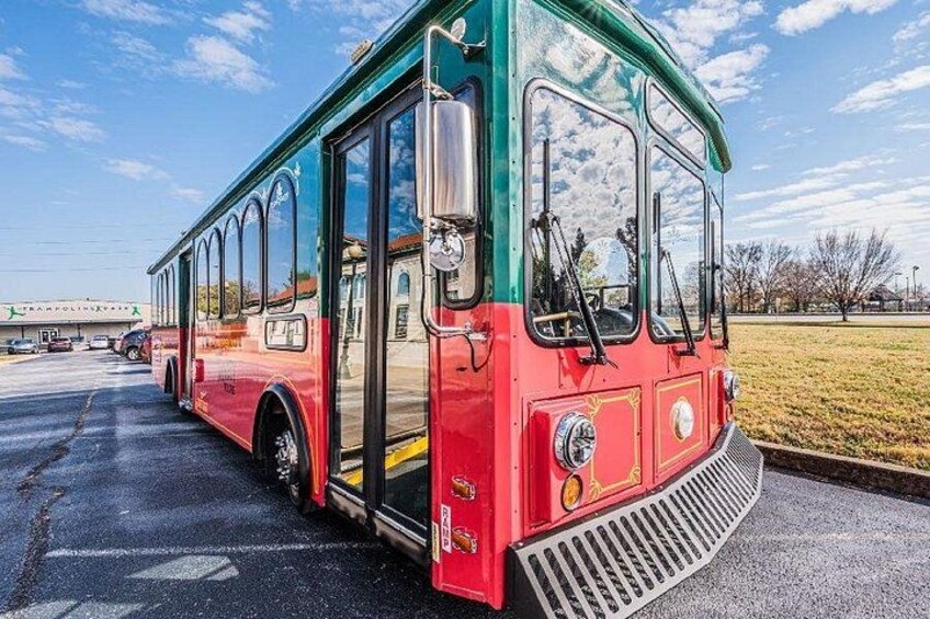 A red and green bus parked in a lot with a building in the background. 3