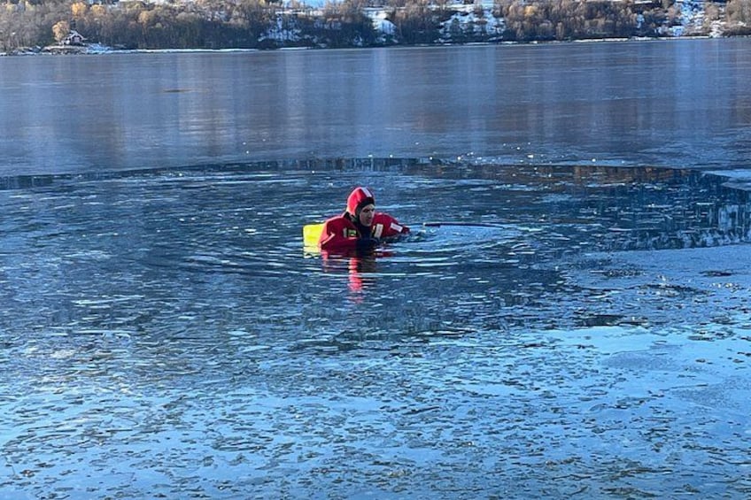A person in a red jacket wading through a partially frozen lake. 5