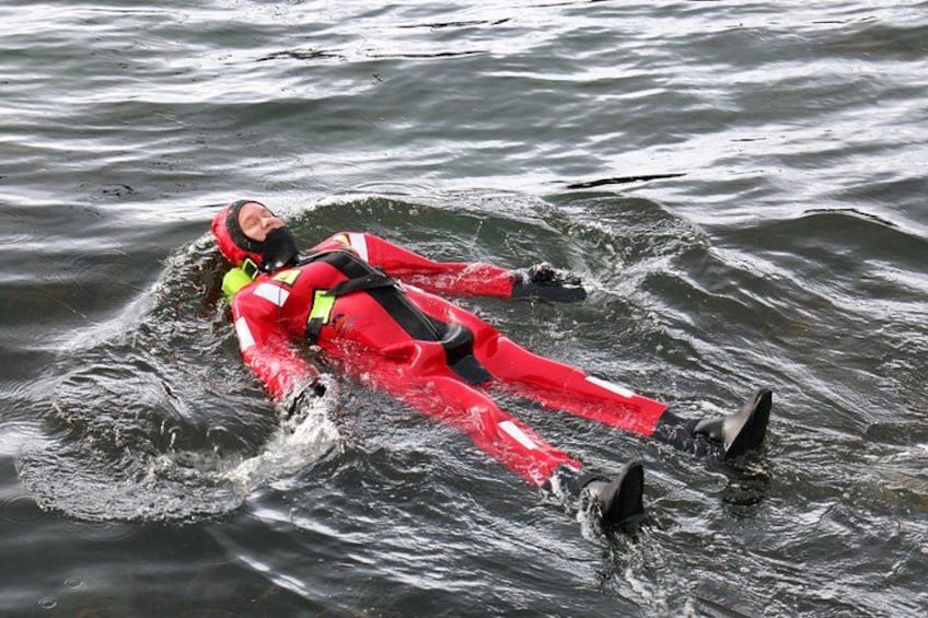 A person in a red wetsuit floating on water. 4