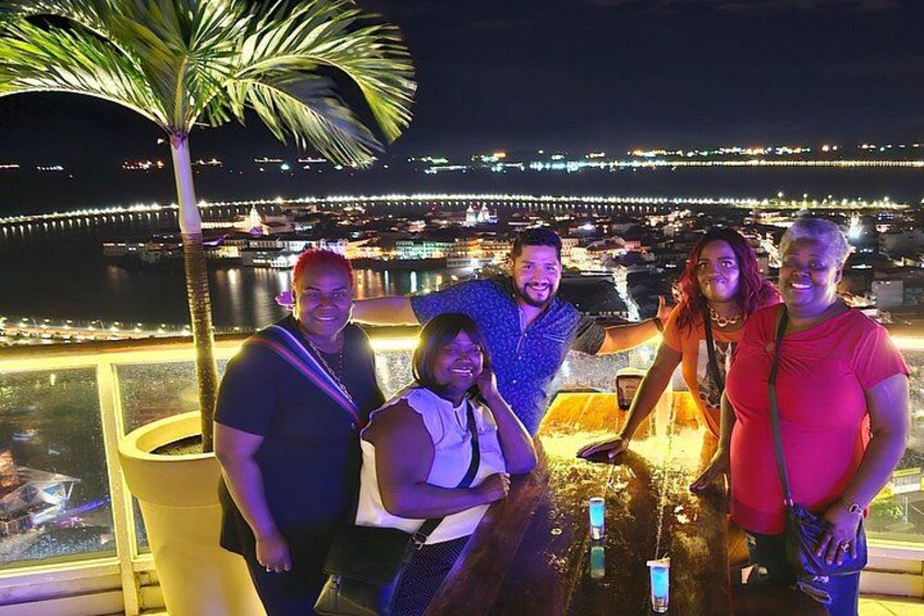 Un grupo de personas en un balcón con vistas a un paisaje urbano nocturno. 5