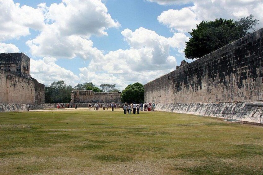 Un extenso campo abierto con un muro de piedra y una estructura piramidal al fondo. 5