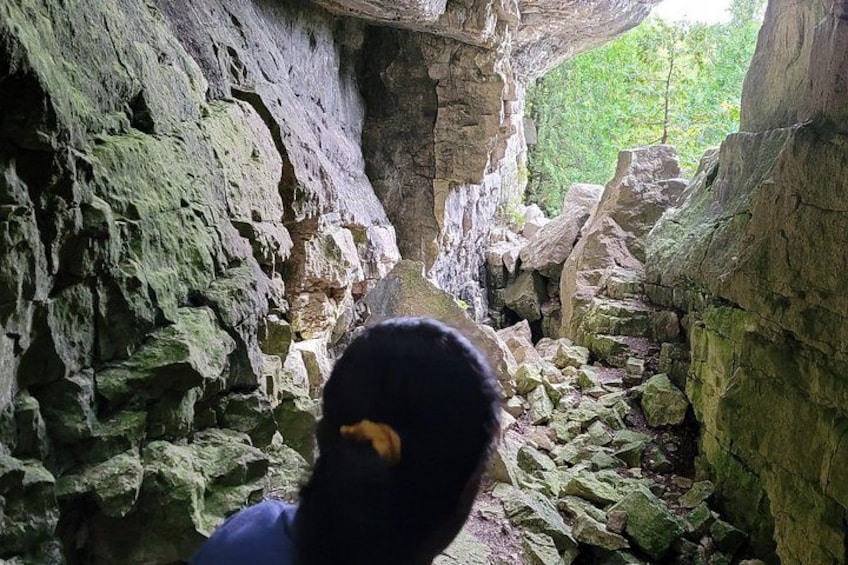 A person inside a cave with rocky walls and a narrow passage. 5