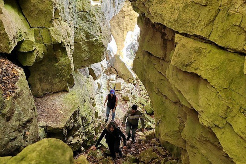 A narrow canyon with rocky walls and a person hiking through it. 2
