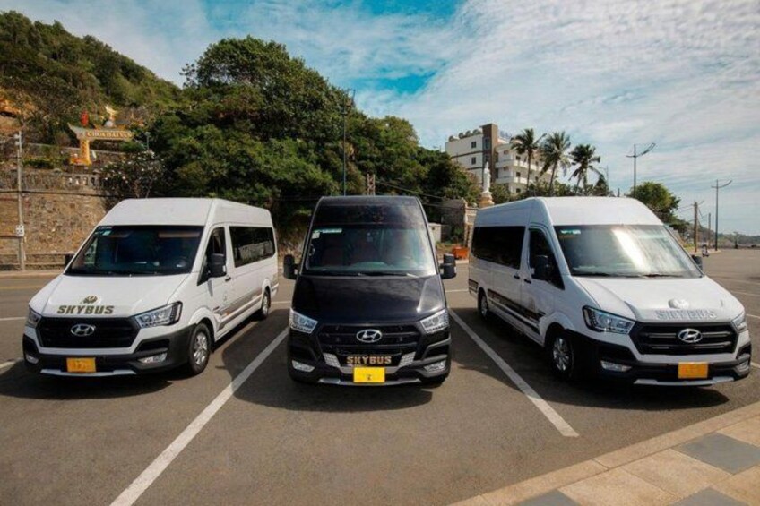 Three vans parked in a row on a road with a clear sky and some trees in the background. 1