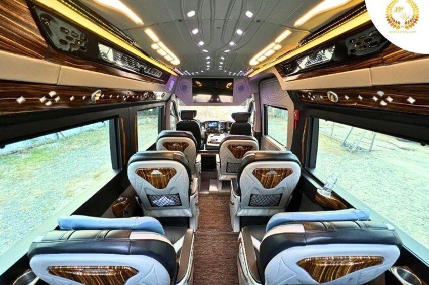 A train interior with leather seats, wooden paneling, and overhead lighting. 5