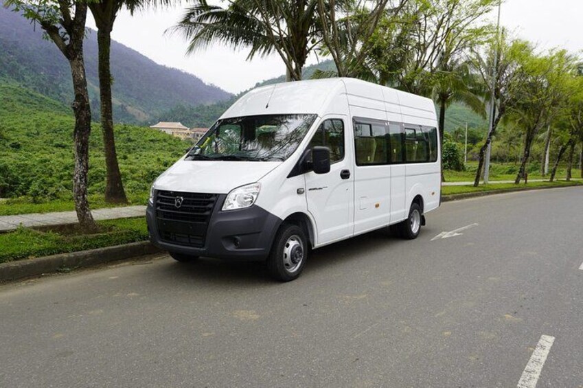 A white van parked on a road with trees and mountains in the background. 4