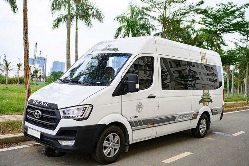 A white van parked on a road with palm trees and a construction site in the background. 1