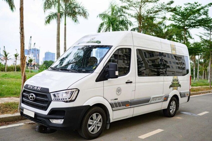 A white van parked on a road with palm trees and a construction site in the background. 2