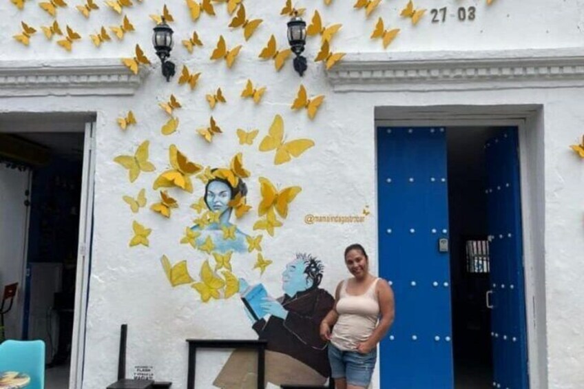 Un edificio con un mural de una mujer y mariposas, una puerta azul y la fecha '21-03' en la pared. 4