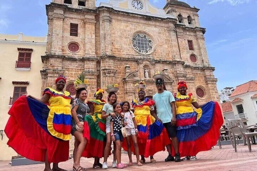 Un grupo de personas con trajes coloridos frente a un edificio histórico con una torre de reloj. 1