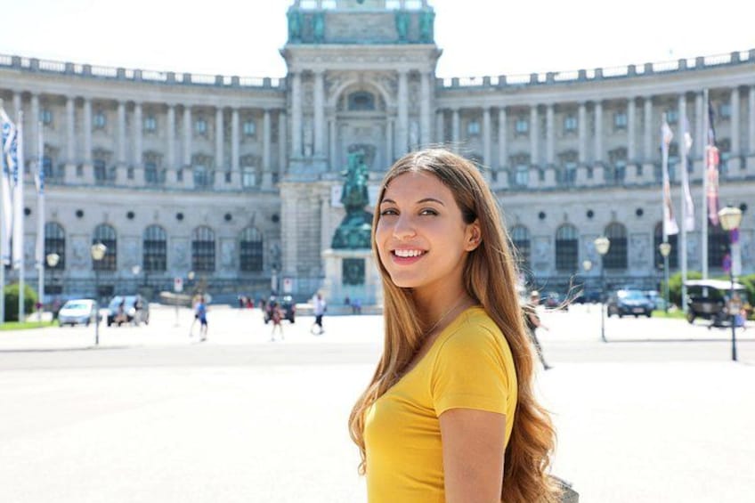 A person in a yellow top standing in front of a large historic building with columns and a statue. 3