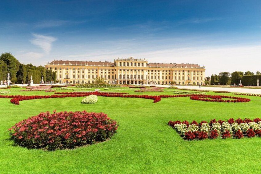 A large classical building with symmetrical gardens and manicured lawns. 1