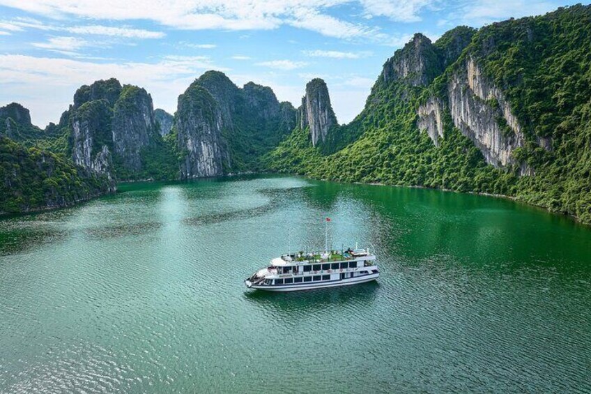 A boat on a calm river surrounded by lush green cliffs. 1