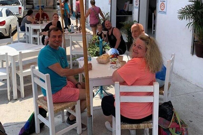 Persone sedute a un caffè all'aperto, con tavoli e sedie. 5