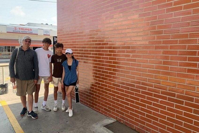 Un gruppo di persone in piedi di fronte a un muro di mattoni, con un edificio sullo sfondo. 2