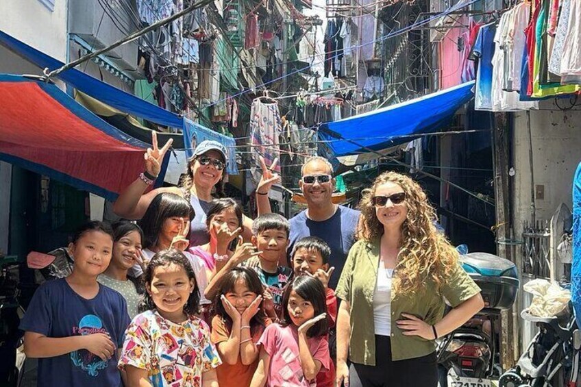 A group of people in a narrow street with clothes hanging overhead. 5