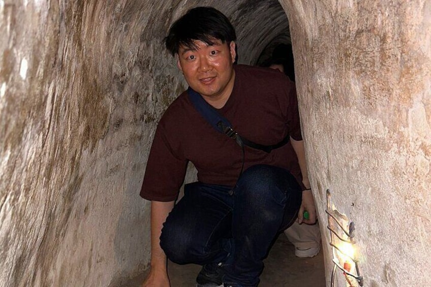 A person crouching in a narrow, rocky passageway. 5