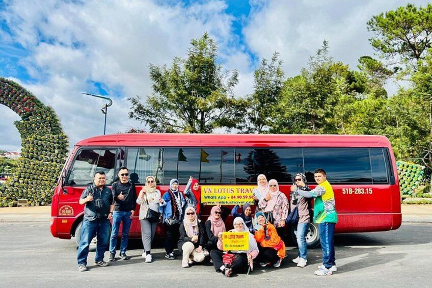 Un grupo de personas posando frente a un autobús rojo con un letrero amarillo. 4