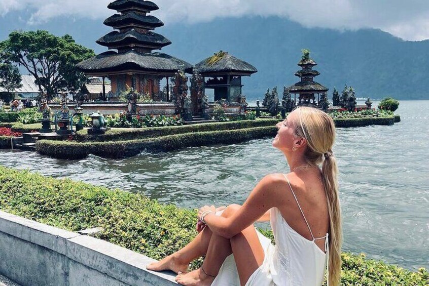 A woman sitting by a lake with pagodas in the background. 5
