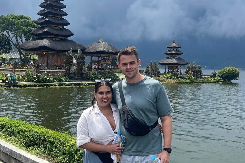 A couple standing by a lake with pagoda-style buildings in the background. 3