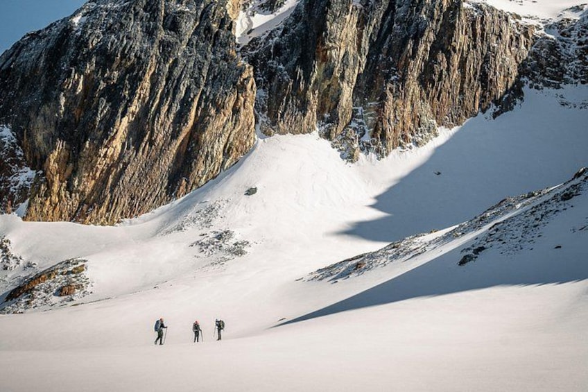 A snowy mountain landscape with three skiers descending a slope. 3