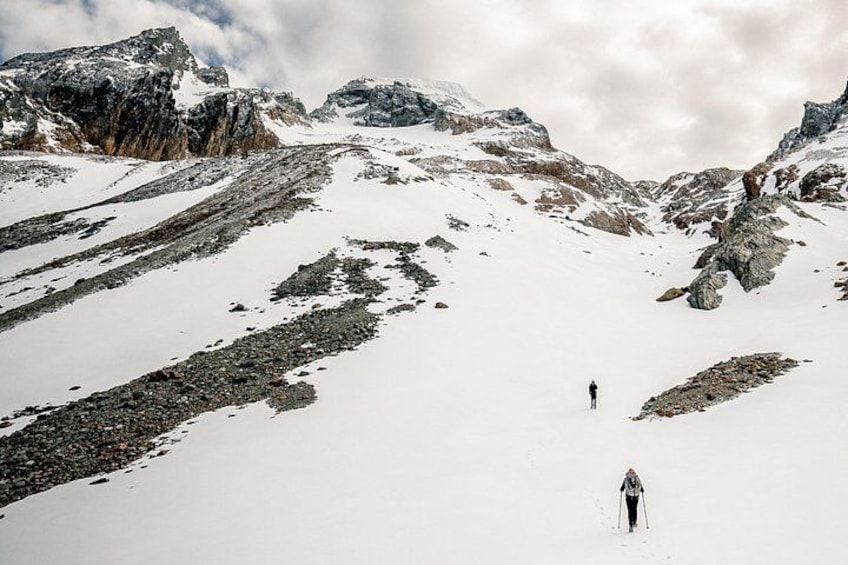 A snowy mountain landscape with two skiers. 2