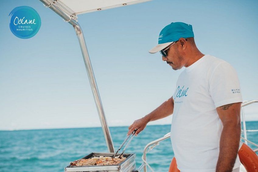 A person grilling on a boat with the ocean in the background. 2