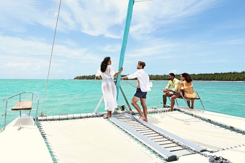 A sailboat with people on deck, calm turquoise sea, and a clear sky. 1