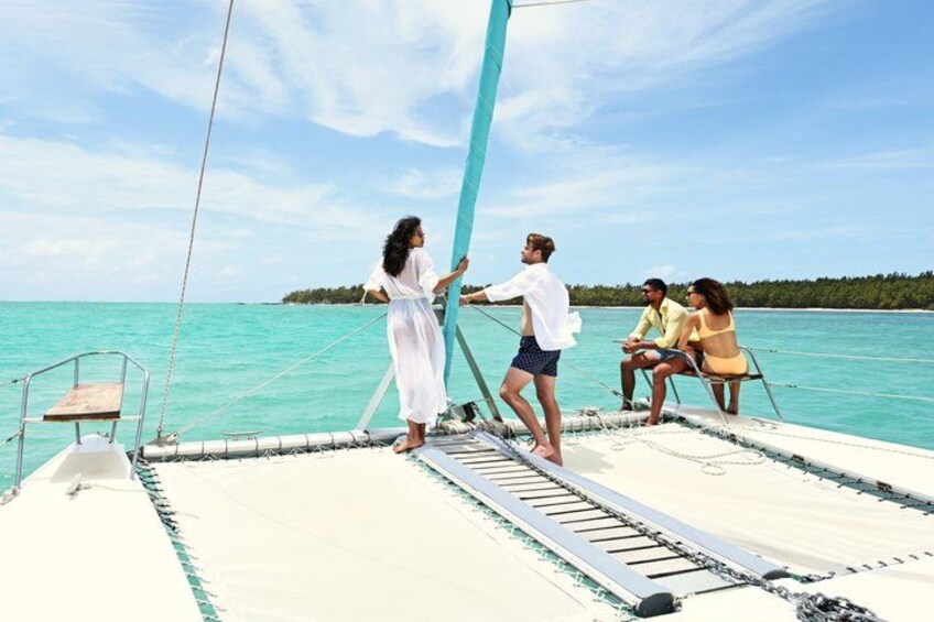 A sailboat on turquoise water with people on deck. 1