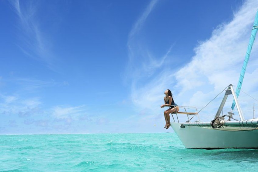 Une femme assise à la proue d’un bateau, une mer turquoise et calme, un ciel dégagé. 5