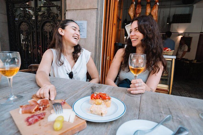 Twee personen zitten aan een buitentafel met eten en drinken. 4