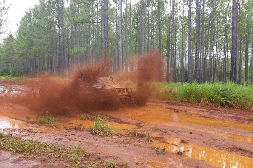 A vehicle driving through a muddy area with water splashes. 2