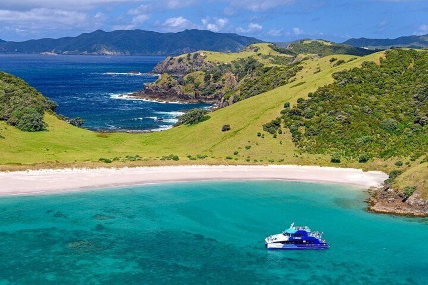 A boat on a turquoise beach surrounded by green hills and mountains. 1